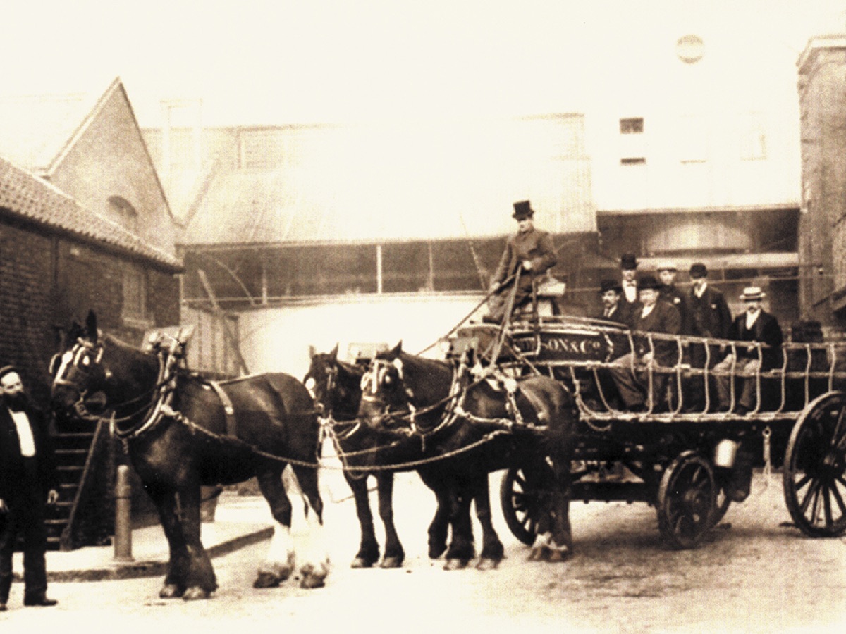 A historic photograph of a horse-drawn distillery cart.