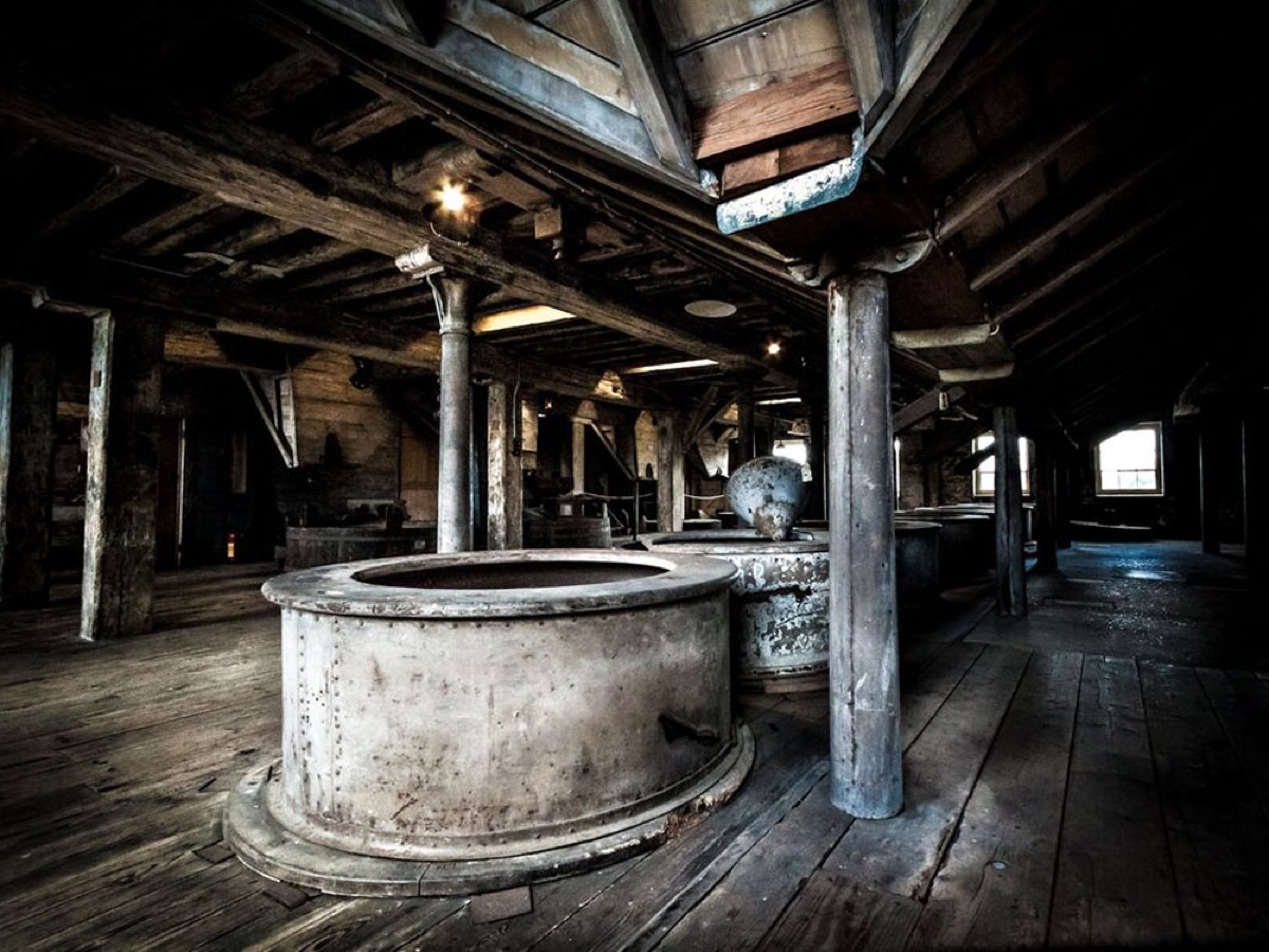 The dim interior of the mill showing great iron and timber grinding tuns.